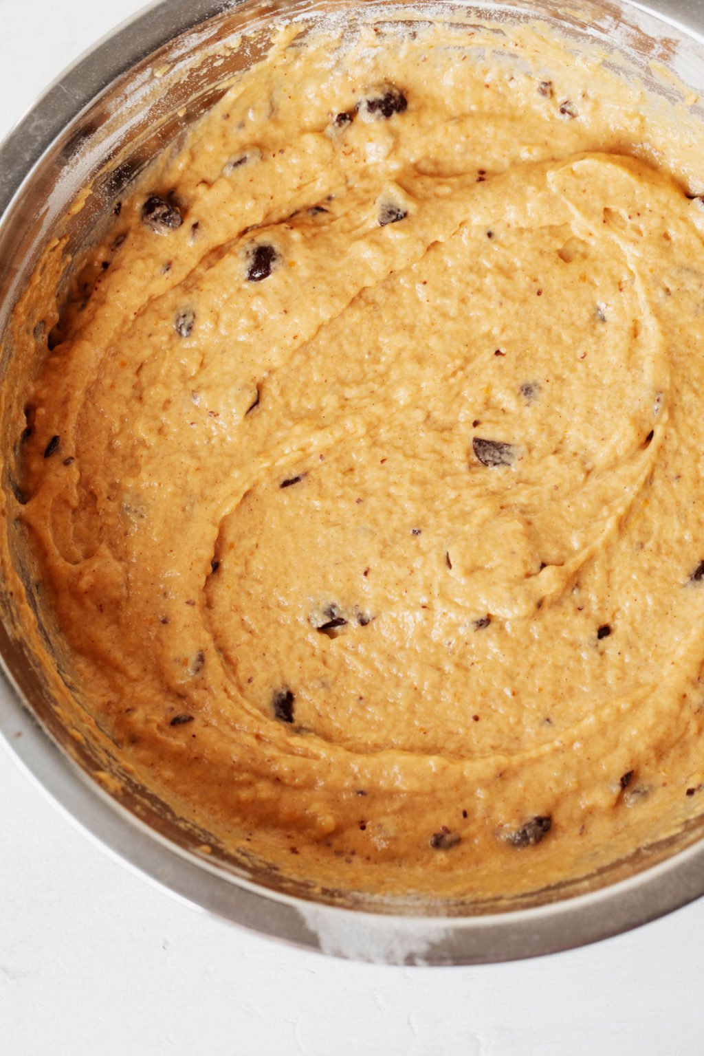 A mixing bowl is full of a pumpkin spiced batter for baking.