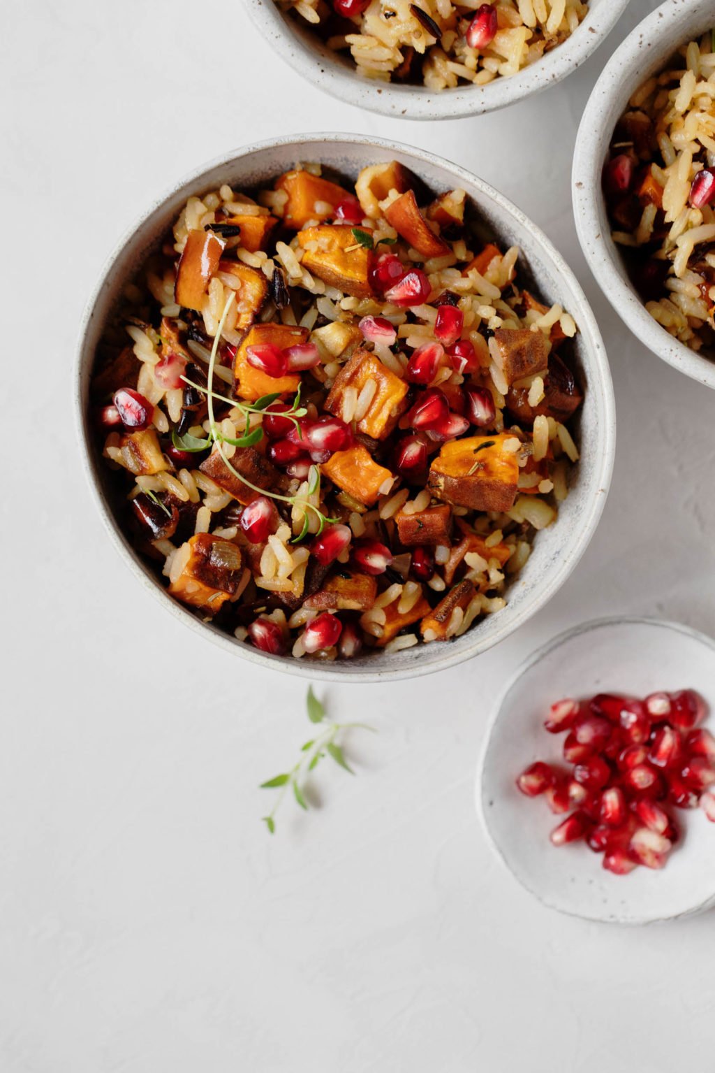 An overhead photograph of a bowl of sweet potatoes, pomegranate arils, and wild rice.
