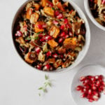 An overhead photograph of a bowl of sweet potatoes, pomegranate arils, and wild rice.