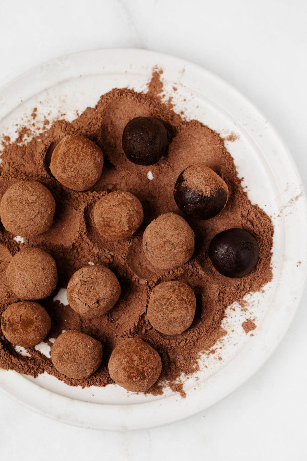 Chocolate truffles are being rolled in cocoa powder.