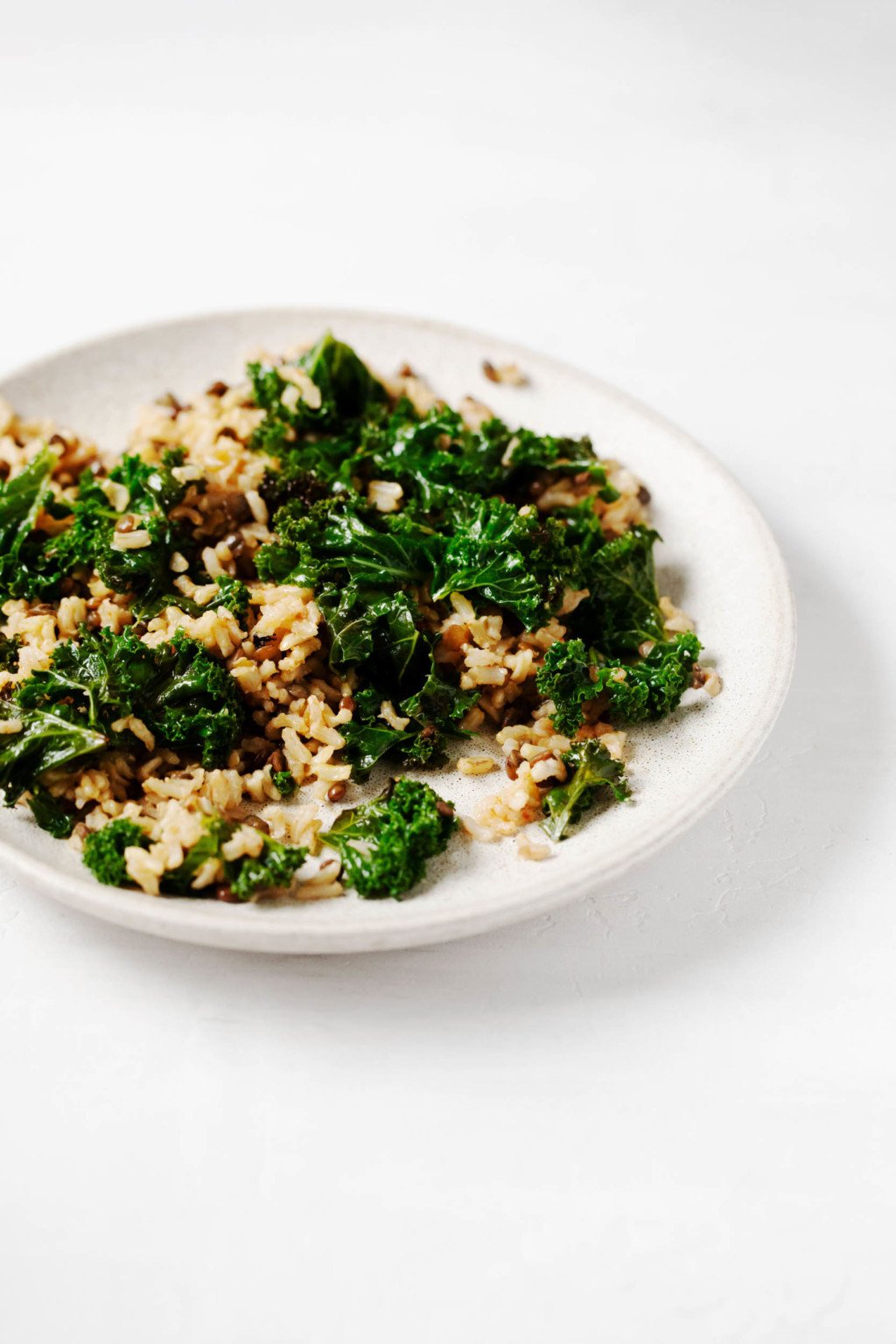 A small serving plate is covered with greens, whole grains, and legumes.