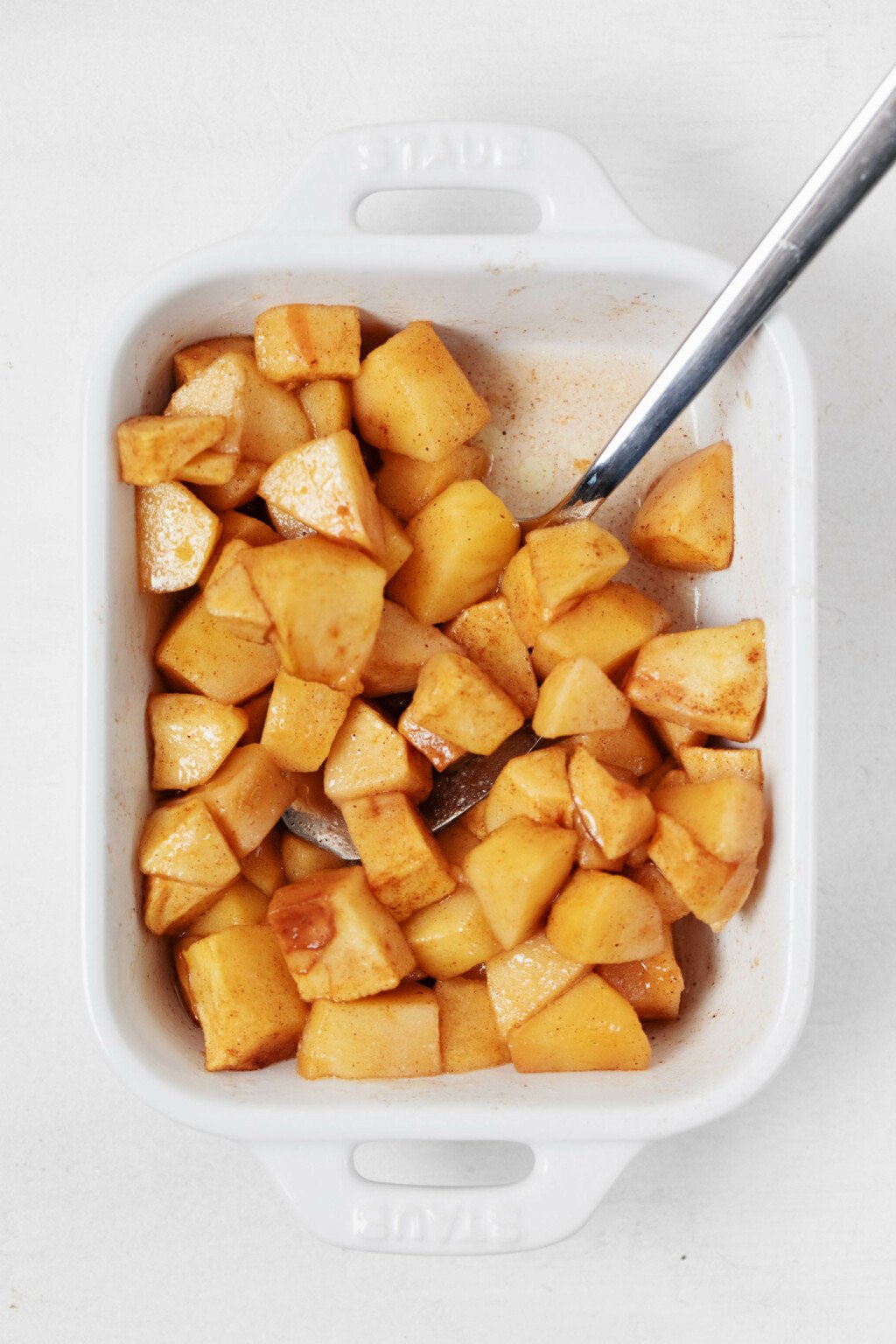 An overhead image of a white baking dish, which is filled with baked apples.