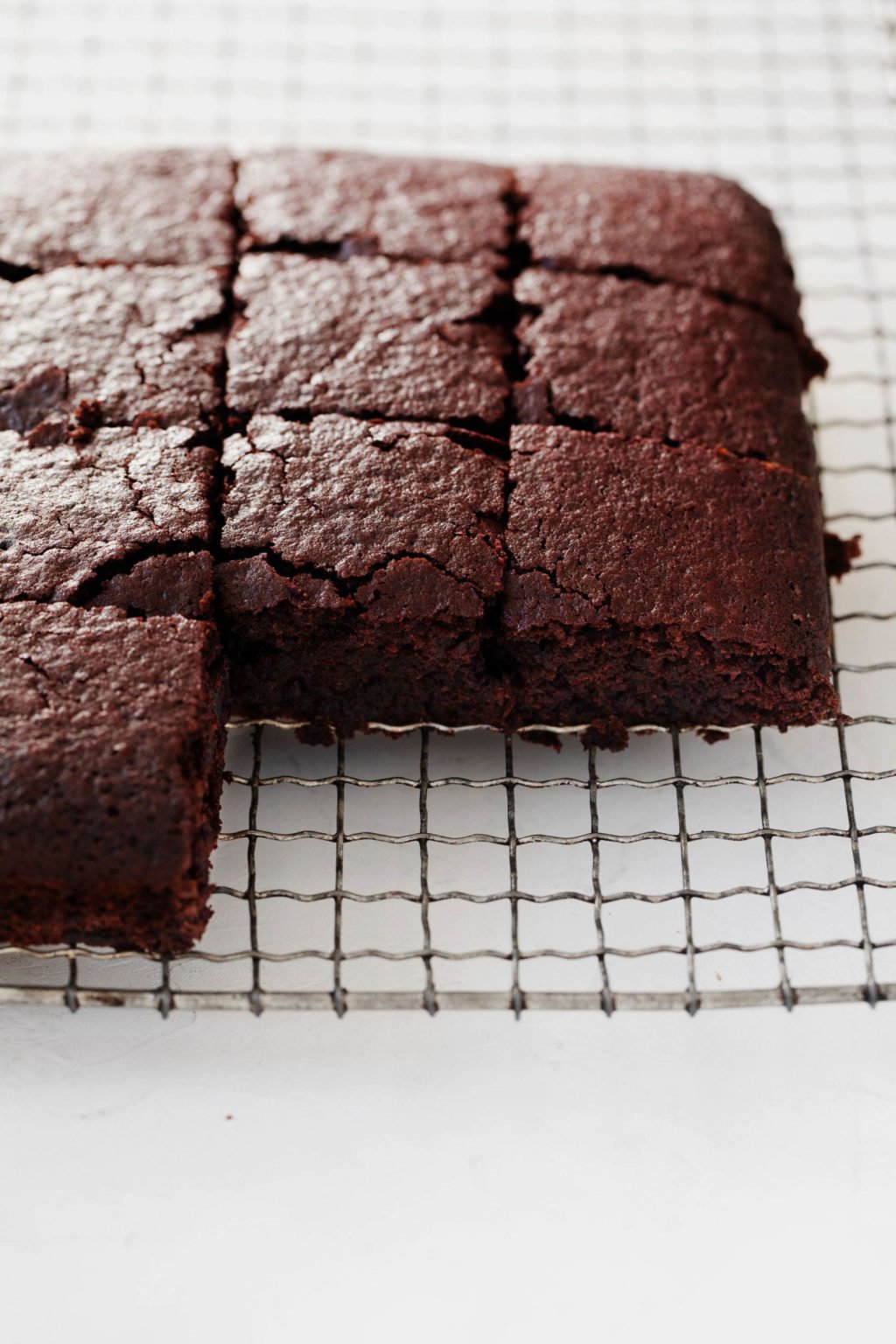 A wire cooling rack has been topped with a square cake, cut into small pieces.