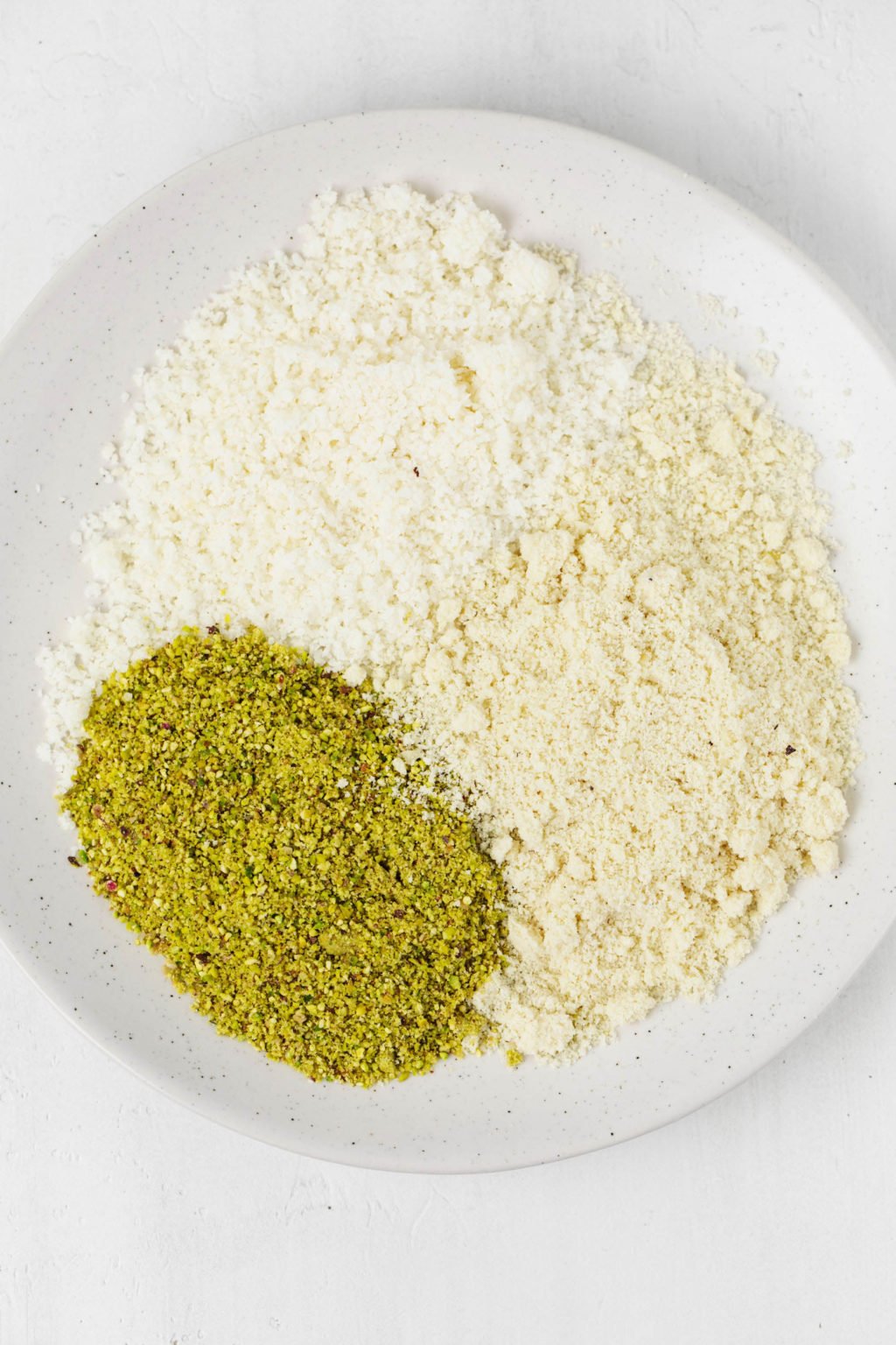 Three different types of baking flours are resting on a white plate.