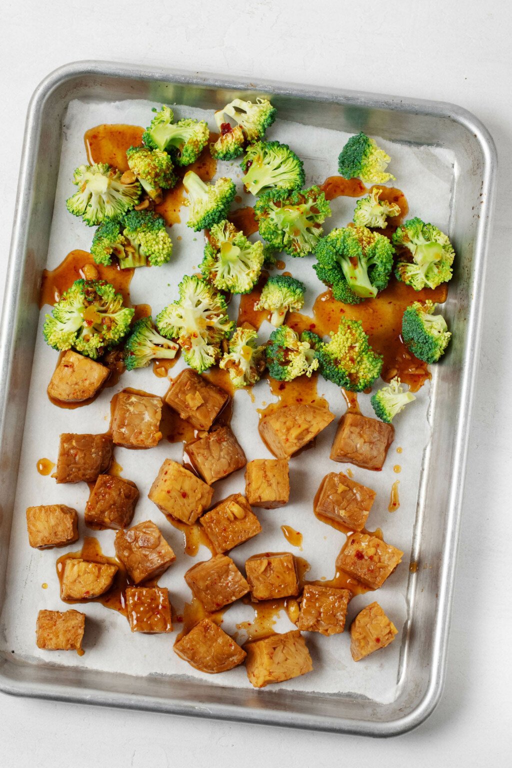 A plant-based protein and broccoli florets are laid out on a metal sheet pan.