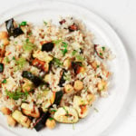 An overhead image of a plate covered in zucchini chickpea rice, which is garnished with fresh dill.