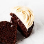 A chocolate peanut butter cupcake has been sliced neatly in half. It's resting on a small dessert plate.