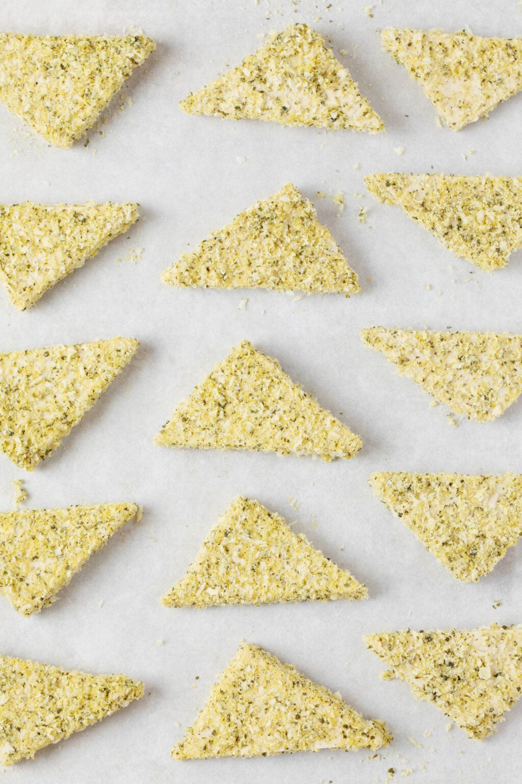 Triangular pieces of tofu have been arranged on white parchment for baking.