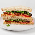 A cross section of a sandwich that has been prepared with tempeh, greens, red pepper, and a sweet potato spread.