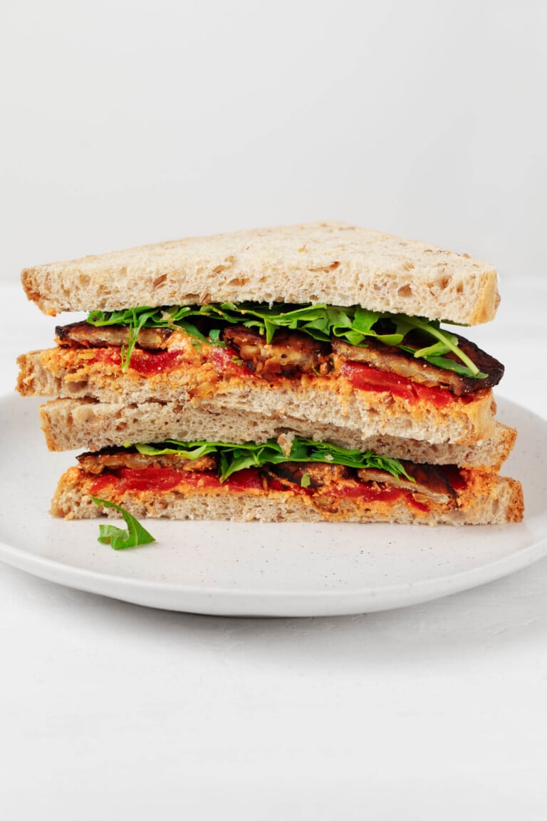 A cross section of a sandwich that has been prepared with tempeh, greens, red pepper, and a sweet potato spread.