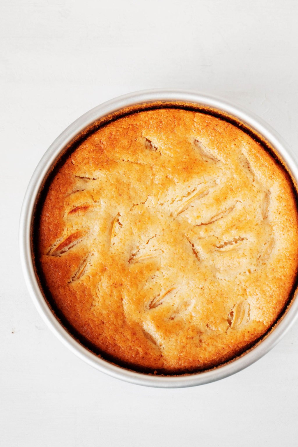 An overhead image of a plant-based, dairy free cake. It has been baked in a round, silver pan.