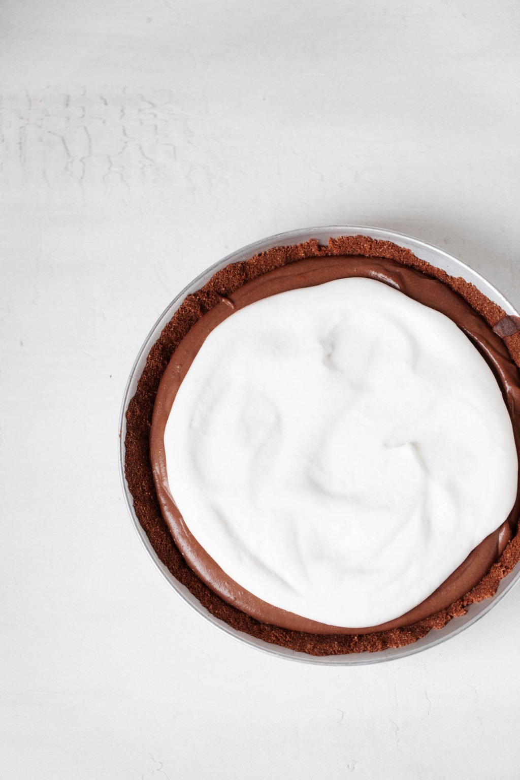 An overhead image of a chocolate pie, topped with whipped cream.