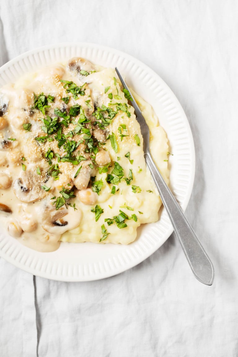 Creamy mashed chickpeas have been piled on top of mashed potatoes with a generous sprinkle of parsley.