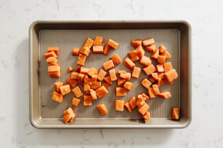 Sweet potatoes are laid out on a nonstick baking pan.