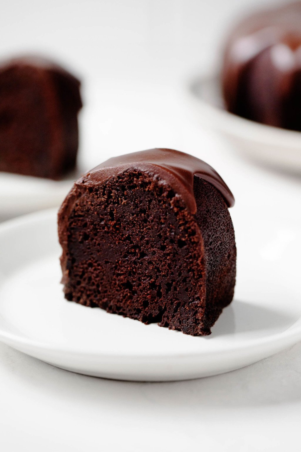 A crosswise sliced piece of glazed cake, with a few additional pieces visible in the bright, white background.