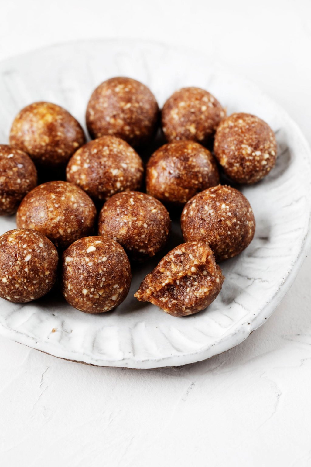 A small, white rimmed plate holds a cluster of vegan energy balls.
