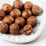 A small, white rimmed plate holds a cluster of vegan energy balls.