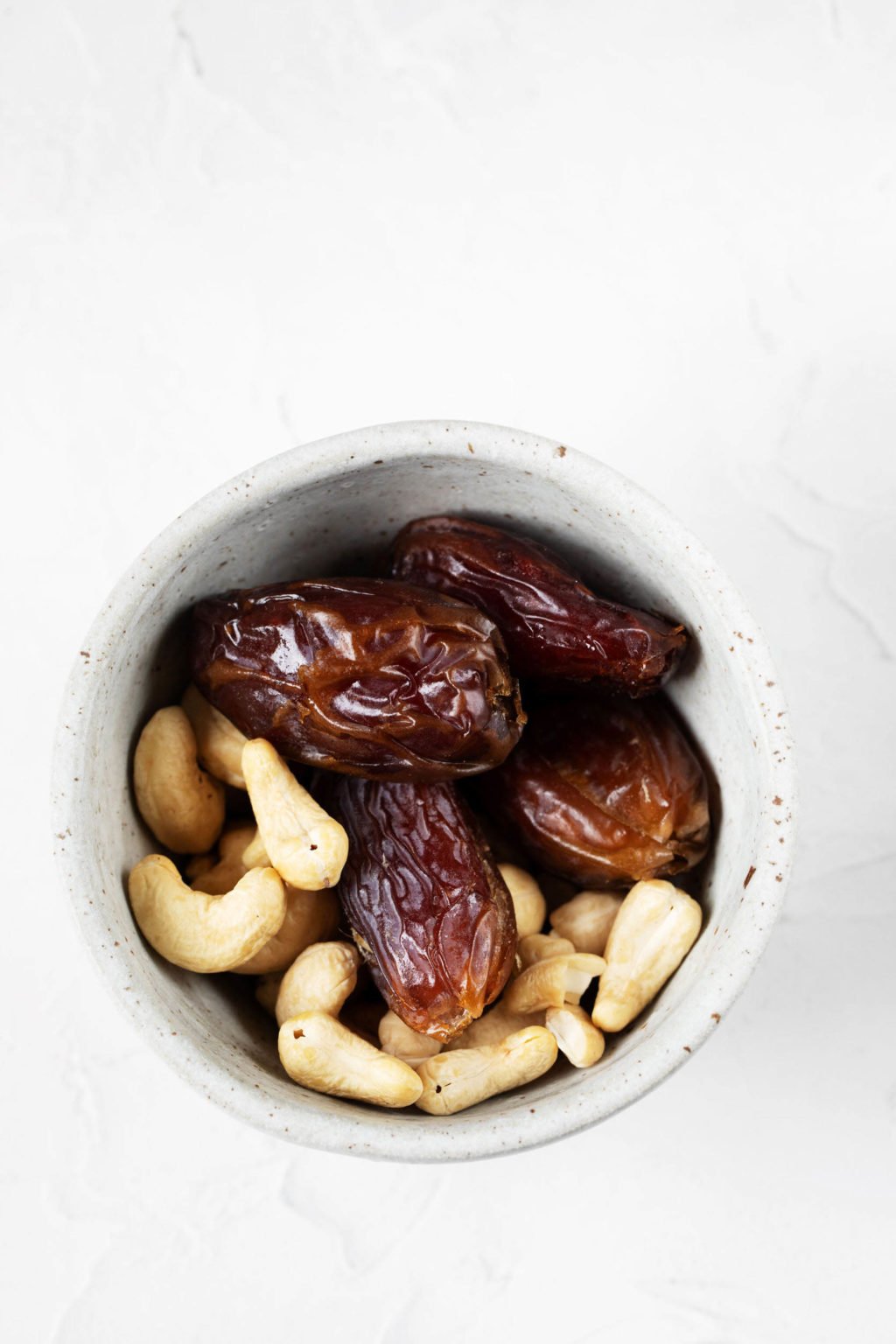 A small pinch bowl holds pitted medjool dates and raw cashews.