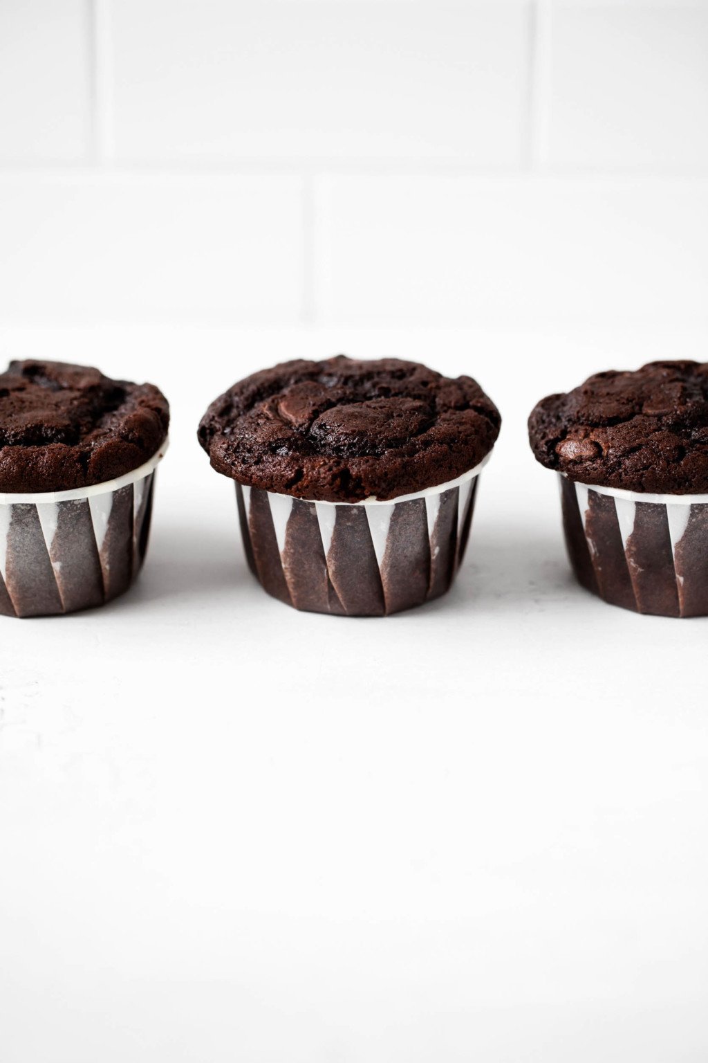 Vegan baked goods with chocolate chips are lined up against a bright, white background.