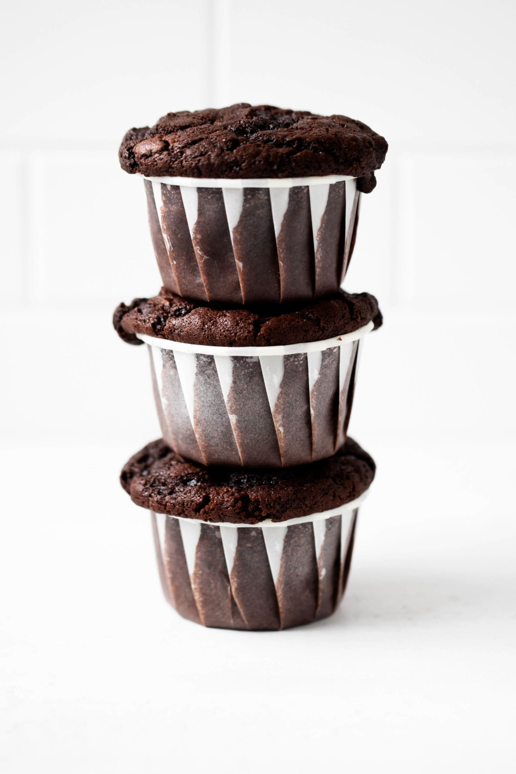 A vertical stack of freshly baked, dark brown muffins.