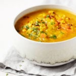 A bowl of spicy cabbage chickpea soup rests on a folded, gray linen napkin.