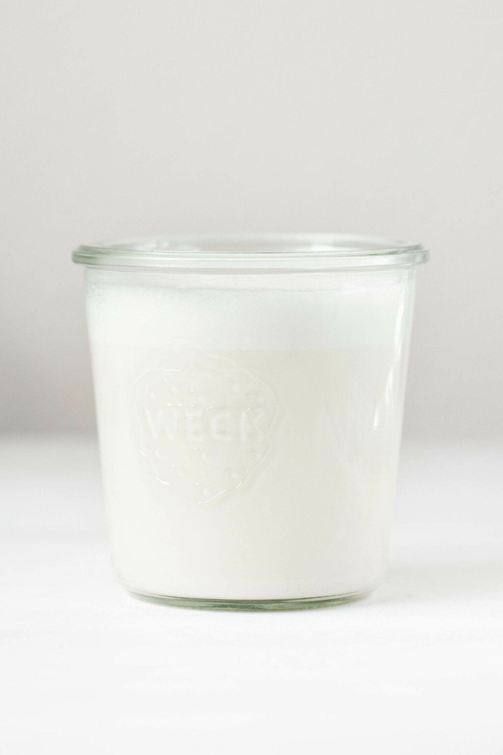 A small mason jar holds a cup of thick white coconut milk.