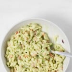 An overhead image of a white, asymmetrical bowl, filled with a vegan pasta salad.