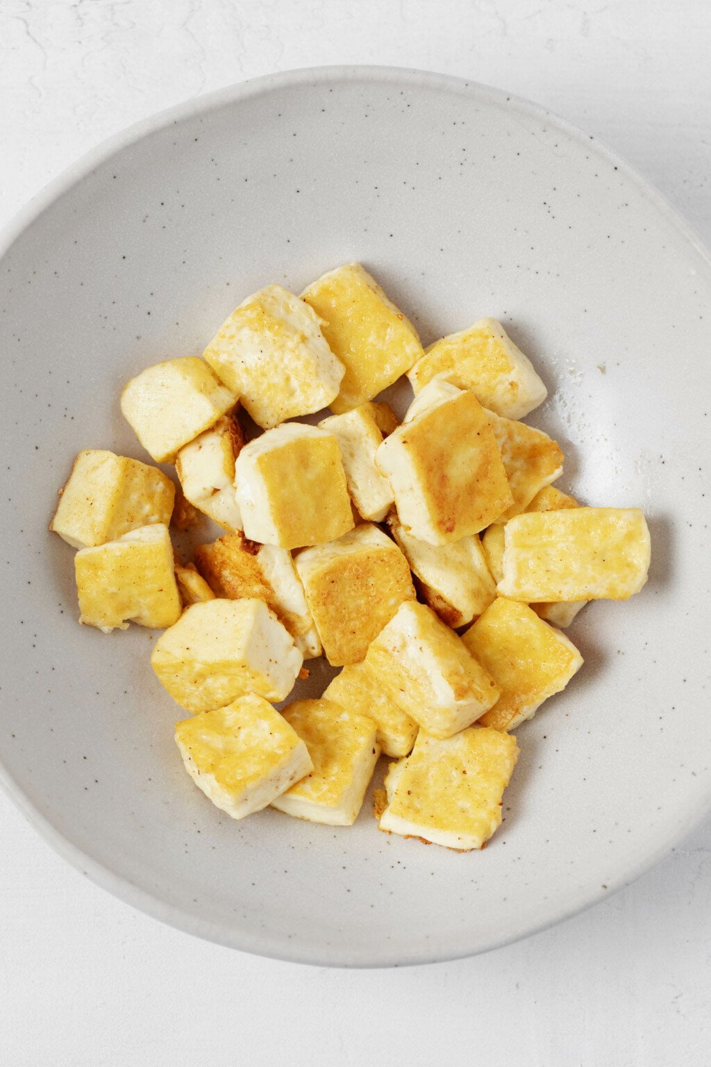 An image of a bowl with lightly browned, golden tofu cubes.