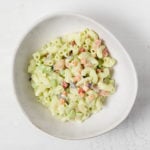 A asymmetrical white bowl holds a creamy vegan pasta salad.