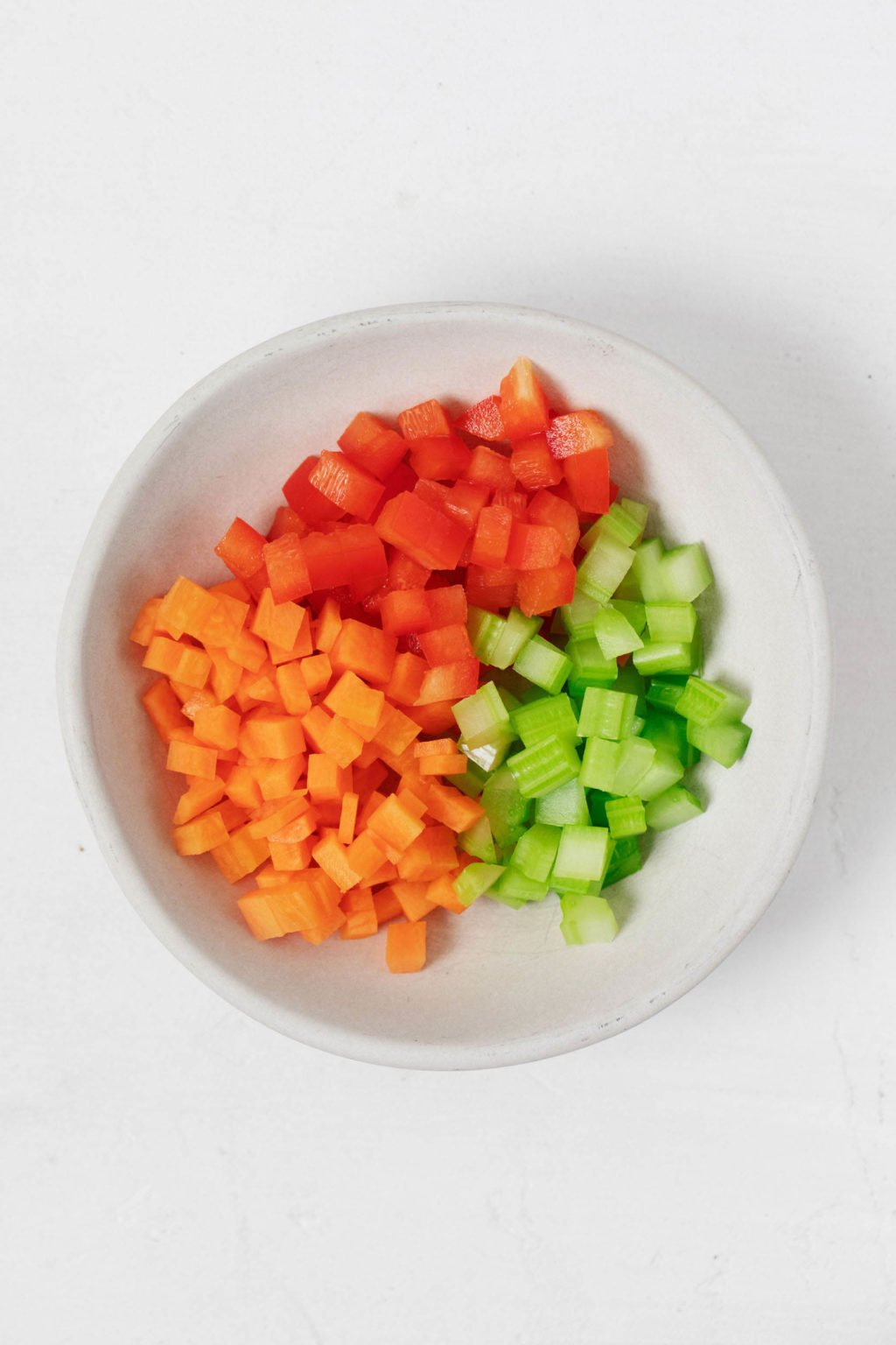 A white bowl holds diced vegetables.