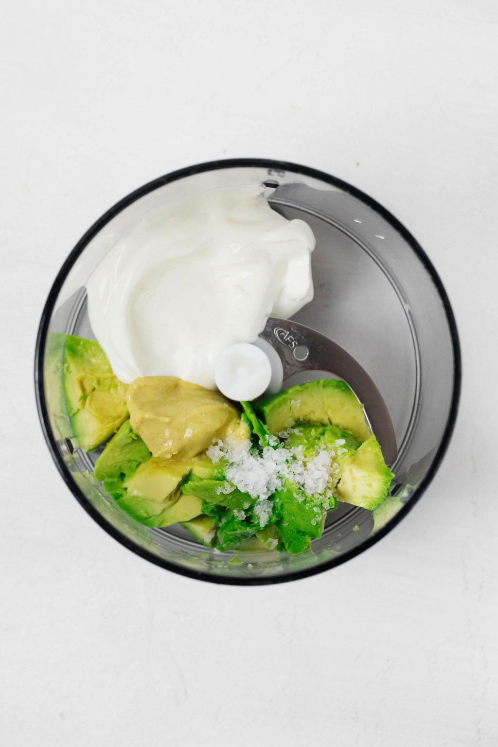 Avocado and yogurt are in the bowl of a food processor fitted with the S blade.