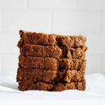 A stack of zucchini bread slices rest on a small piece of white parchment paper.