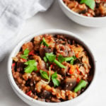 An image of stewed eggplant tomato lentils with fresh parsley on top.