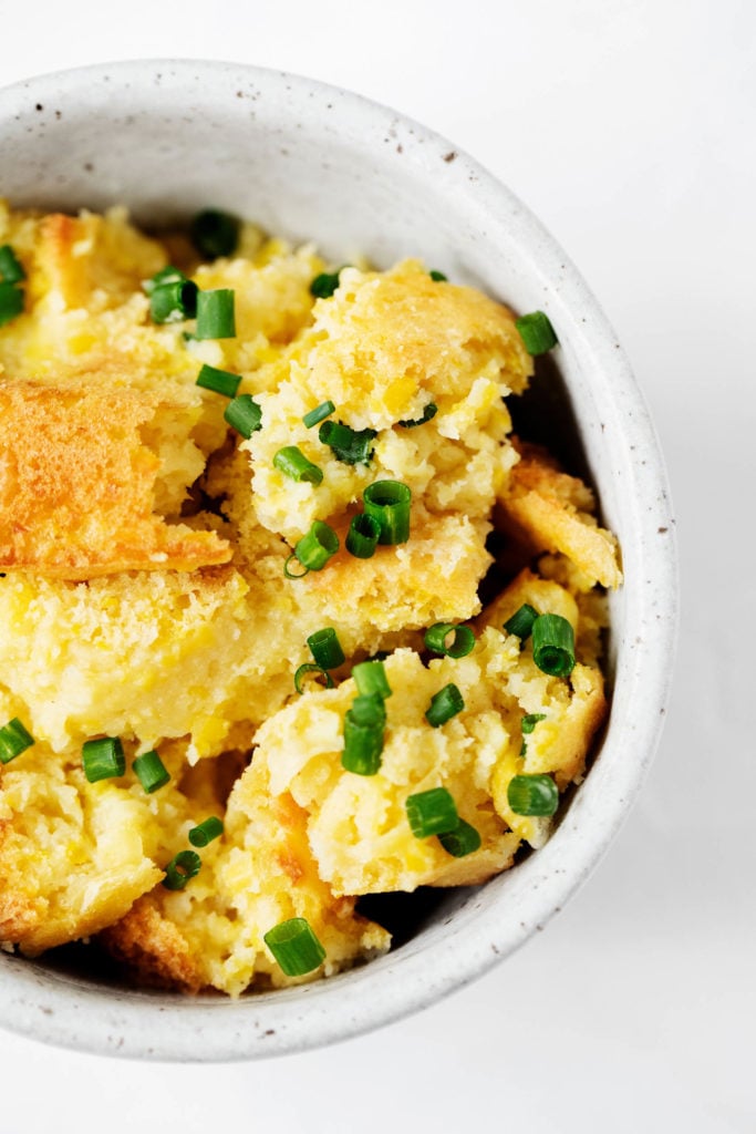 Close up, overhead shot of a creamy vegan corn pudding, crumbled and served in a small bowl.