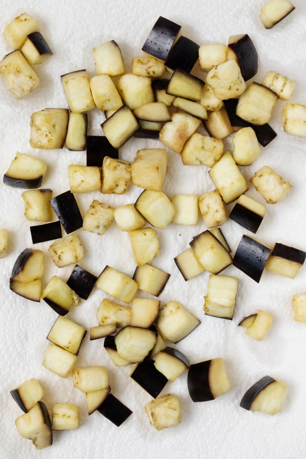 An overhead image of salted eggplant cubes, which are resting on a white tea towel.