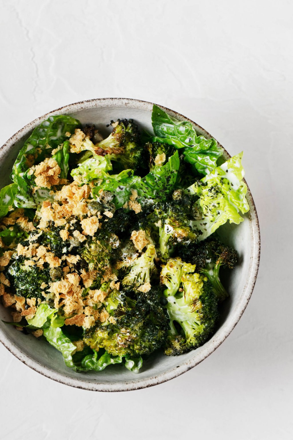 An overhead shot of a bright green dish of crispy roasted broccoli Caesar salad.