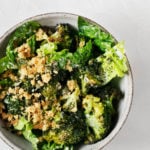 An overhead shot of a bright green dish of crispy roasted broccoli Caesar salad.