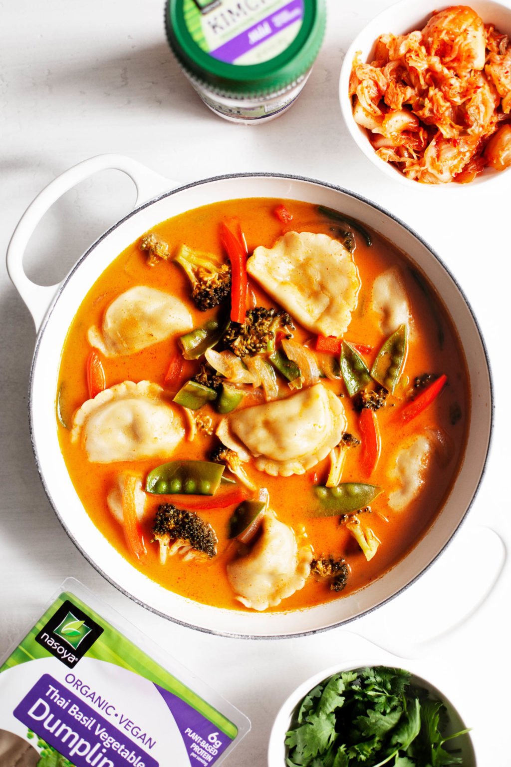 A bowl of red curry dumpling soup, made with the Nasoya brand kimchi as an accompaniment.