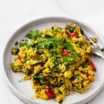 An angled photograph of a vegan breakfast plate of tofu vegetable quinoa scramble.