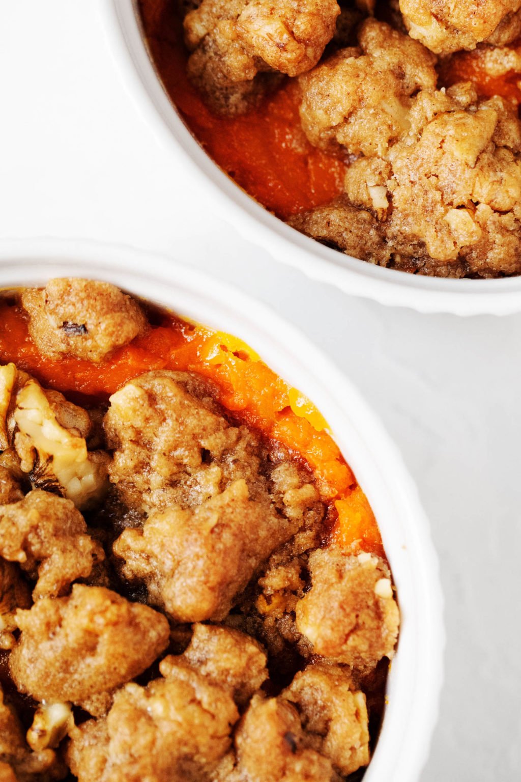 A zoomed in photograph of a streusel topping, sitting on top of mini casseroles in ramekin dishes.