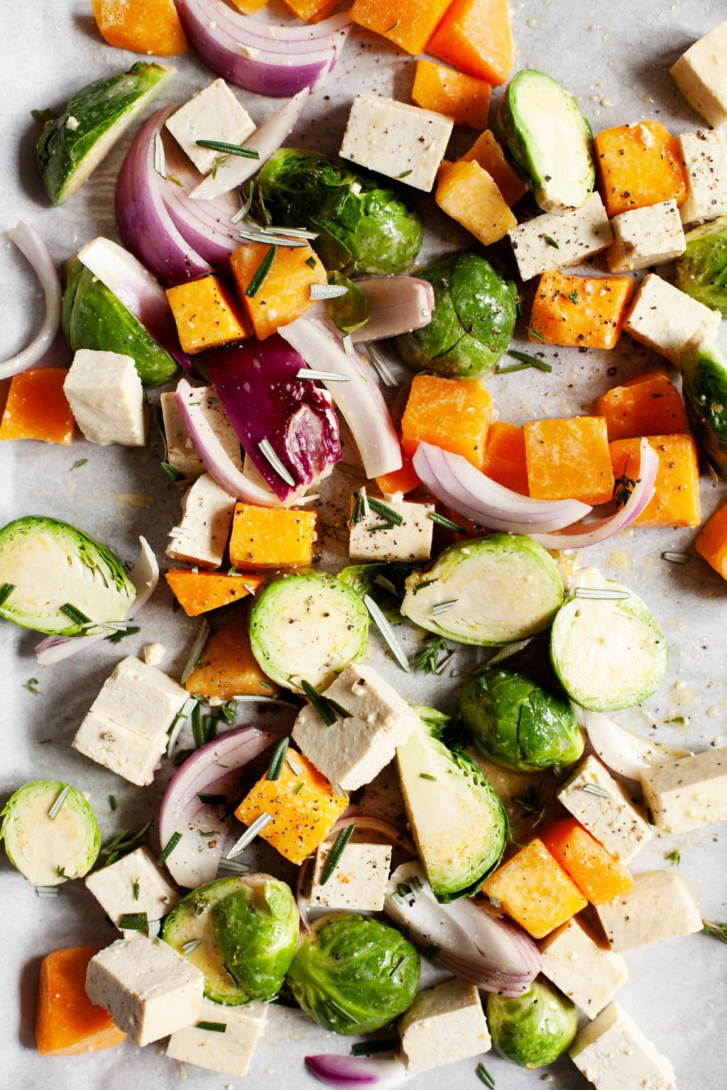 A sheet pan covered with autumn vegetables and tofu, ready for baking.
