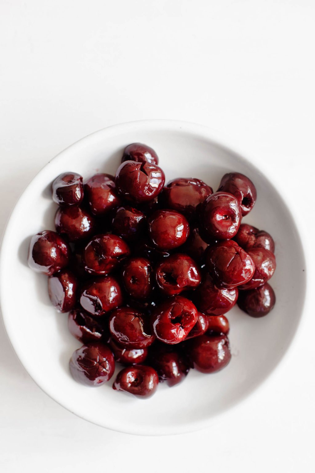 A bowl of plump and shiny dark, sweet cherries.