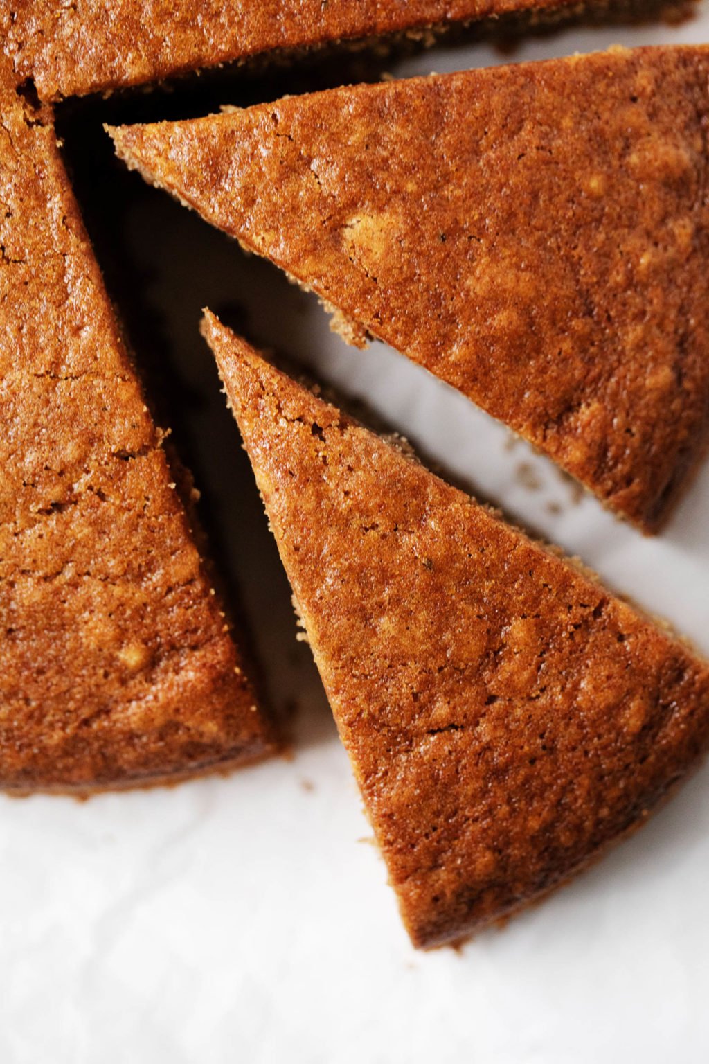 A zoomed in image of round gingerbread cake, which has just had a perfect slice cut out of it.