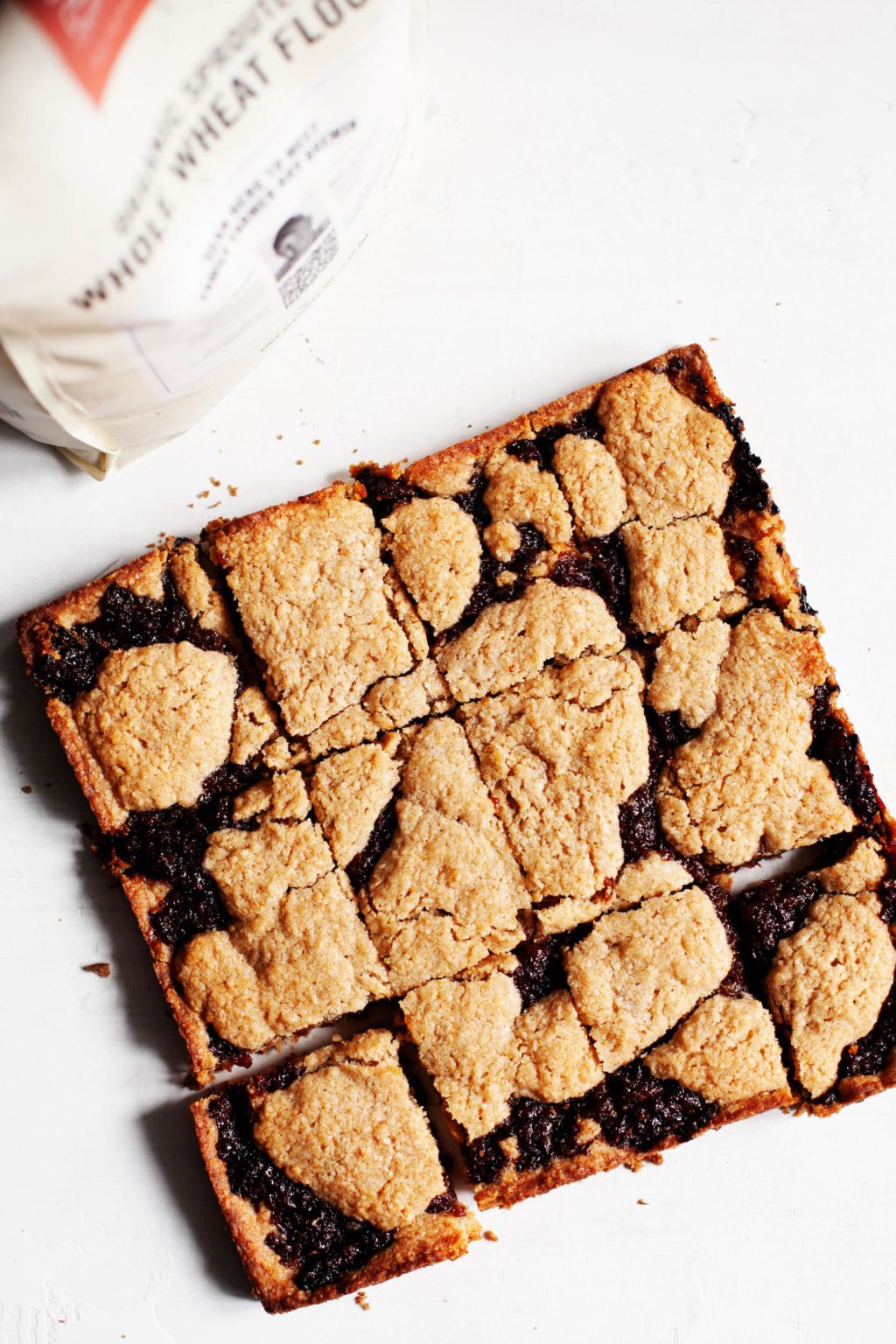 Freshly baked, plant-based whole wheat raisin bars, accompanied by a bag of whole wheat flour.