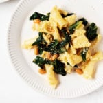 Two white porcelain plates hold portions of a simple, plant-based pasta with beans and greens.