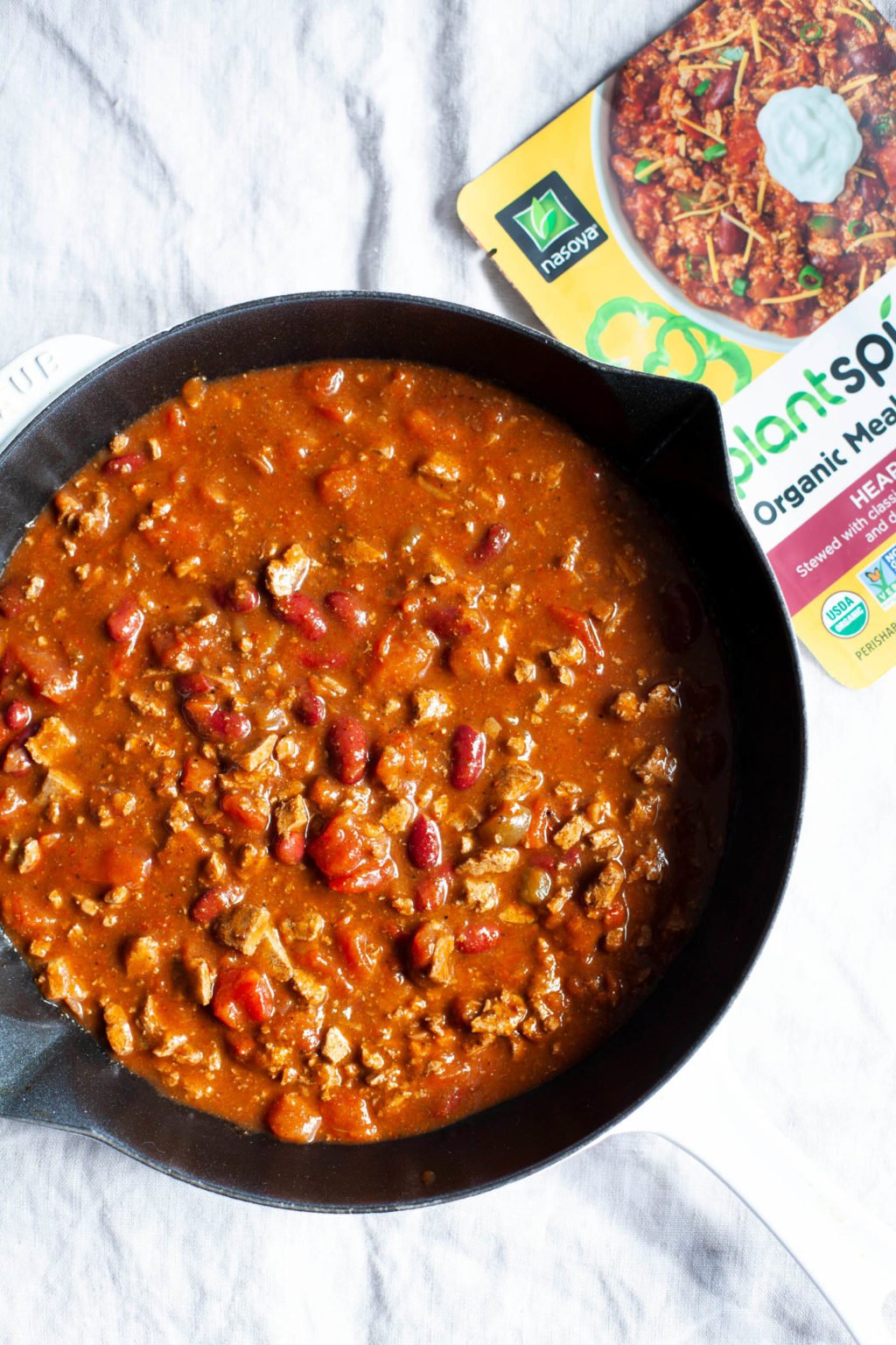 A large, cast iron skillet is filled with a bean-based chili.