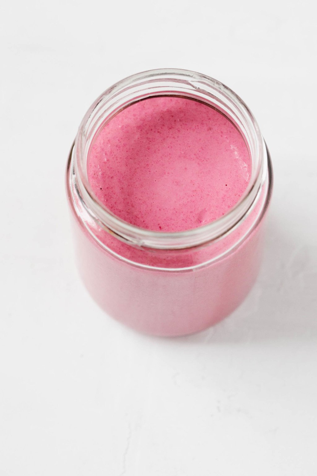 An overhead image of a glass jar filled with vegan tahini beet dressing.