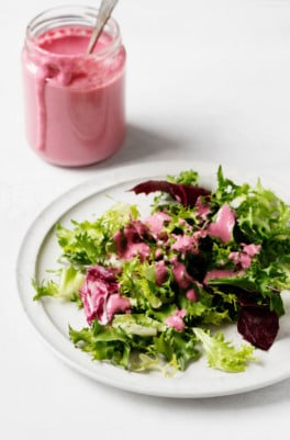 A small green salad has been drizzled with a creamy pink plant-based dressing.