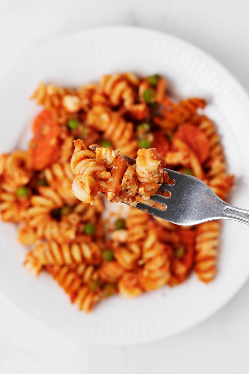 A dish of pasta, vegetables, and vegan cheese.