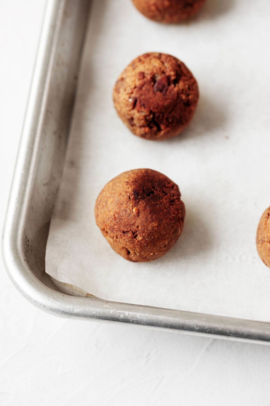 A parchment lined, silver, rimmed baking sheet holds a vegan protein dish that's just come out of the oven.